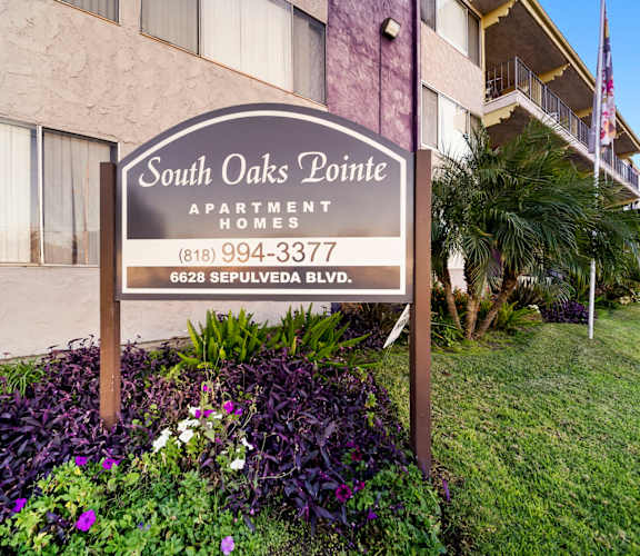 A sign for South Oaks Pointe Apartments stands in front of a building.