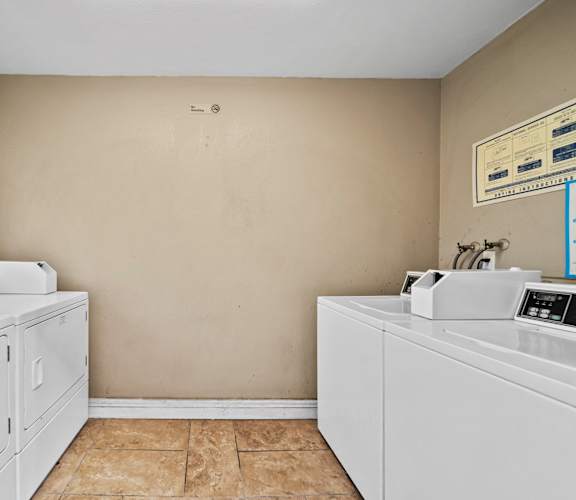 A laundry room with two washing machines and a dryer.