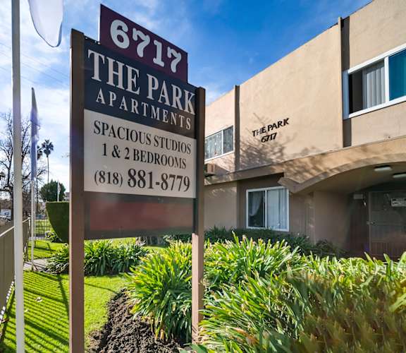 A sign for 6717 The Park Apartments is displayed in front of a building.