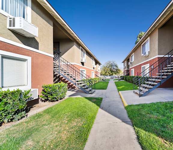 A pathway leads between two rows of apartment buildings.