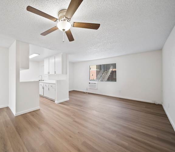 A room with a ceiling fan and wooden flooring.