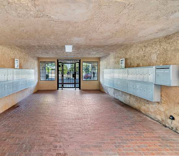 A long hallway with a brick floor and white lockers on the wall.