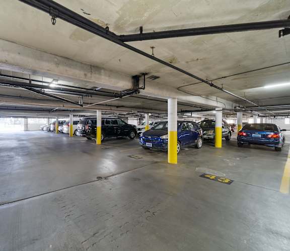 A parking garage with cars parked and yellow poles.