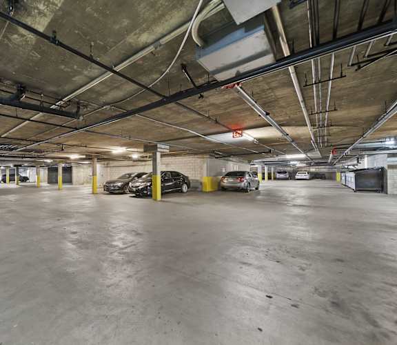 A parking garage with concrete floors and yellow poles.