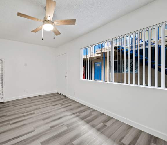 A room with a ceiling fan and a window with bars.