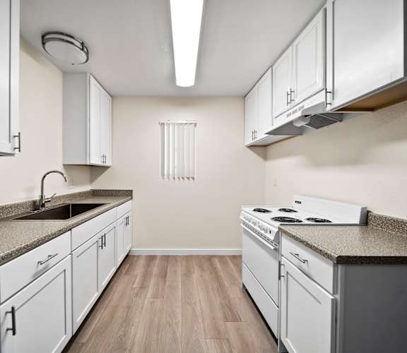 A kitchen with white cabinets and a granite countertop.