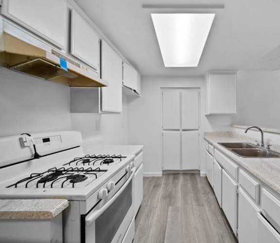 A modern kitchen with white cabinets and a white gas stove.