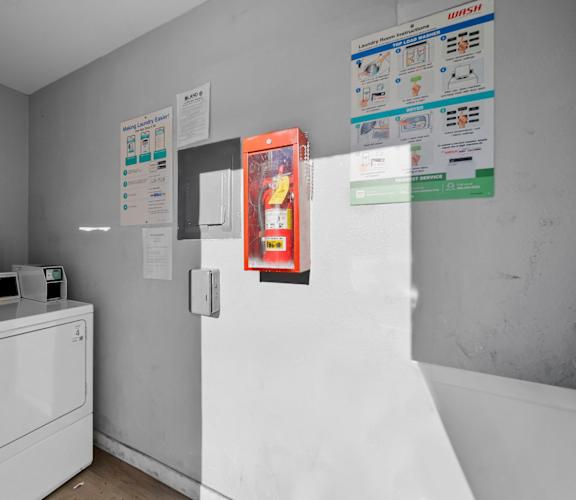 A white washing machine sits in a laundry room with a white dryer.