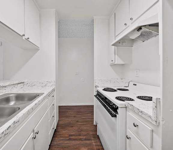 A kitchen with white cabinets and a marble countertop.