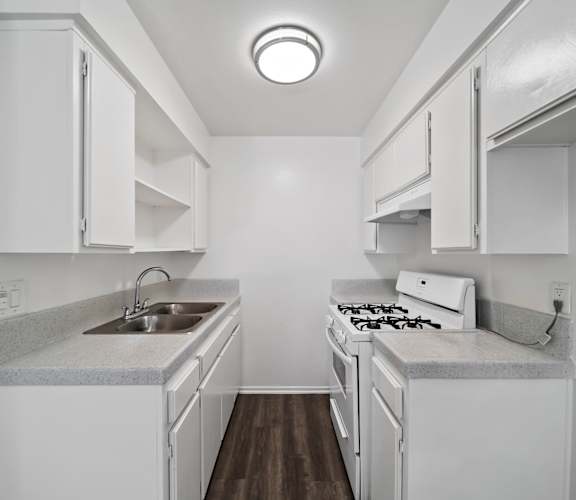 A small white kitchen with a sink and stove.
