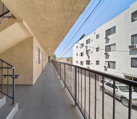 A long, narrow hallway with a metal railing and steps leading up to a building.
