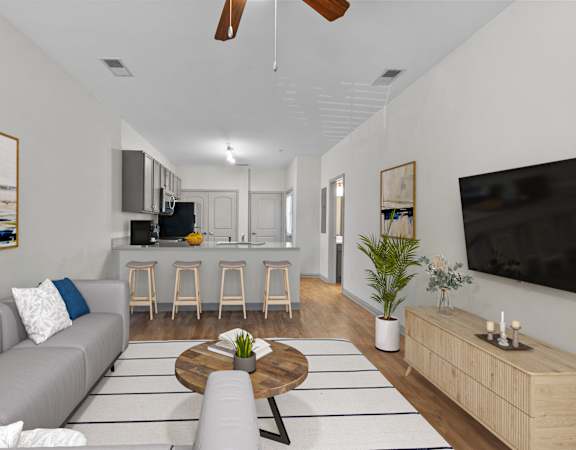 a living room with a couch and a table in front of a kitchen