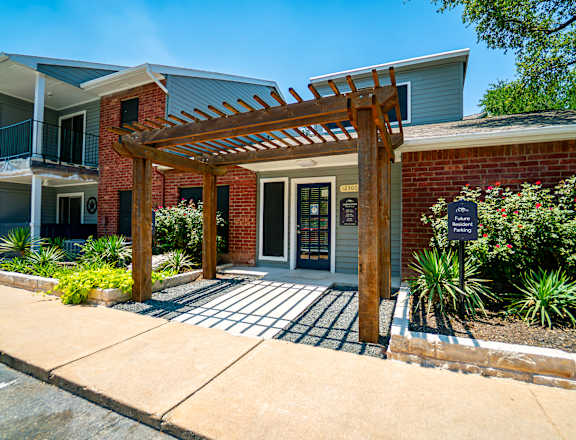 A building with a wooden pergola and a black signboard.