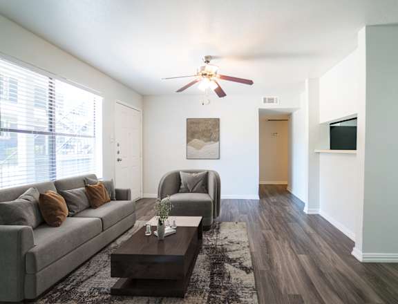 A living room with a grey couch, a coffee table, and a ceiling fan.