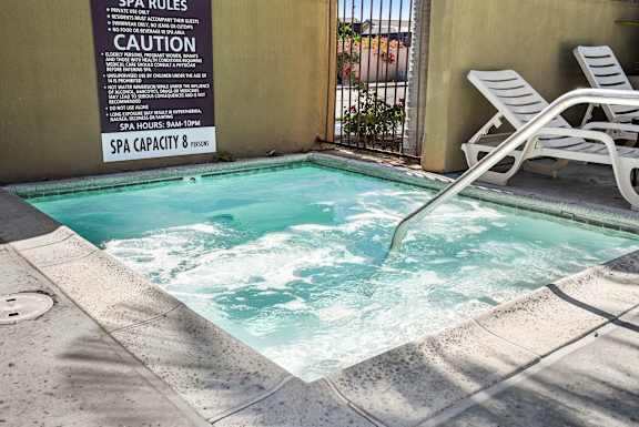 a small pool of water next to a building with two chairs