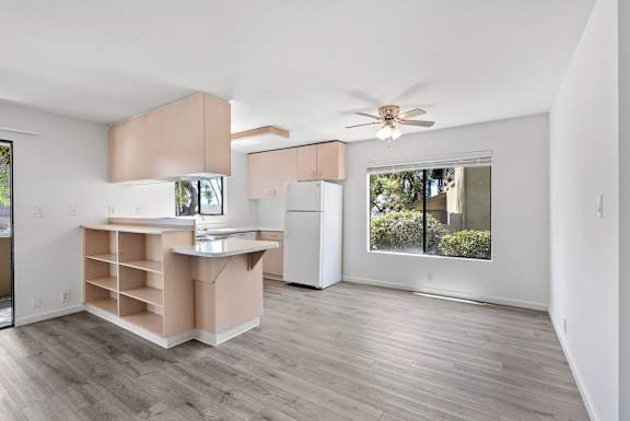 a living room with a kitchen and a ceiling fan