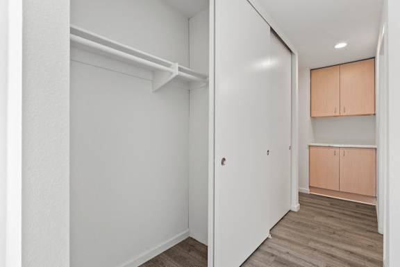 an empty room with white walls and wood flooring and a closet