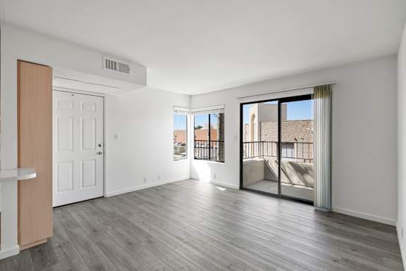 an empty living room with a door to a balcony