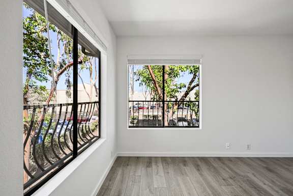 an empty living room with large windows and a balcony
