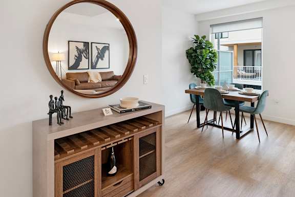 a living room and dining room with a table and a mirror