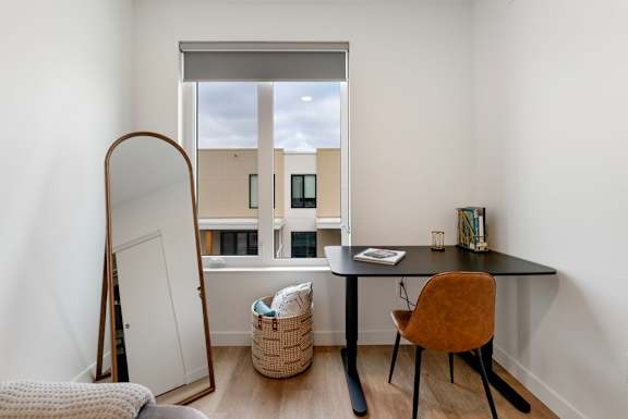 a desk and a mirror in a room with a window