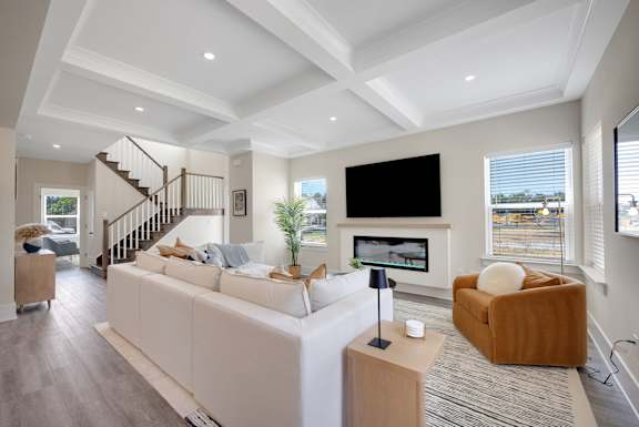 A modern living room with a white couch and a wooden staircase.