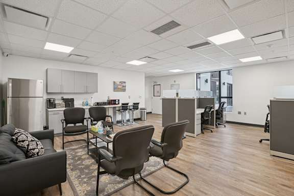 A modern office space with a couch, chairs, and a coffee table.