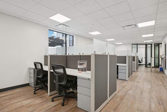 A modern office with wood floors and white walls.