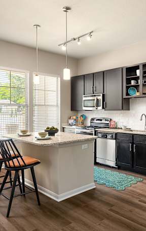 A kitchen with a stainless steel refrigerator and wooden floors.