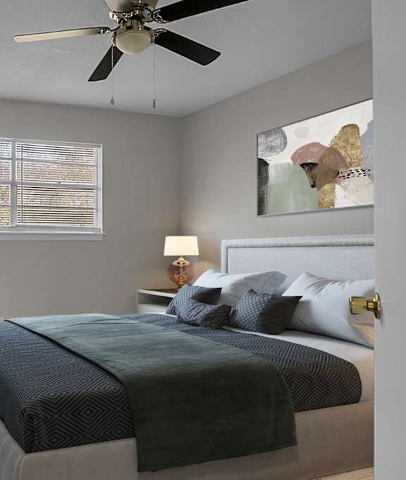 A bedroom with a bed, a ceiling fan, and a potted plant.