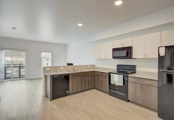 an empty kitchen with wood flooring and stainless steel appliances