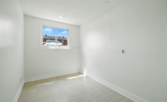 A white gate is in front of a building with a brown door.