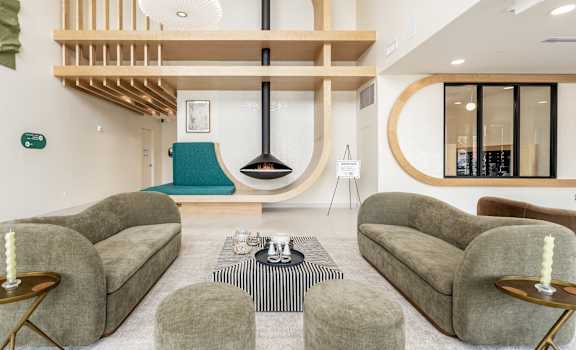 A modern living room with a grey sofa, a black and white striped rug, and a wooden coffee table.