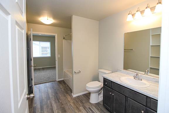 A bathroom with a toilet, sink, and mirror.