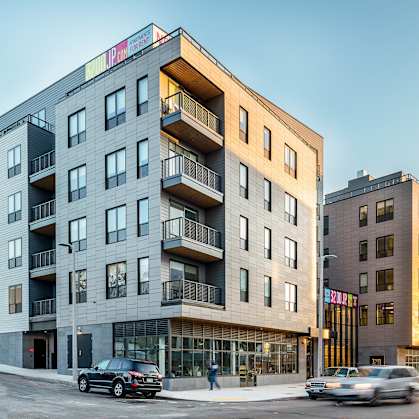 A modern apartment building with cars parked in front.