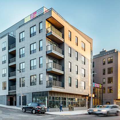 A modern apartment building with cars parked in front.