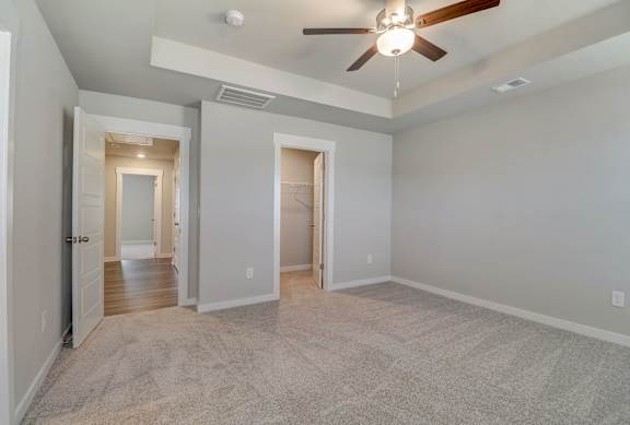 A room with a ceiling fan and carpeted floor.