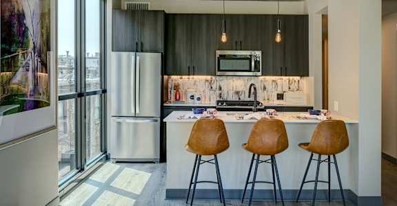 A kitchen with a bar stool and a fridge. at The Mason Apartments, Illinois, 60607
