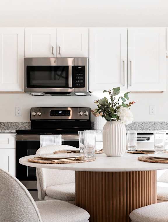 a kitchen with white cabinets and a table and chairs