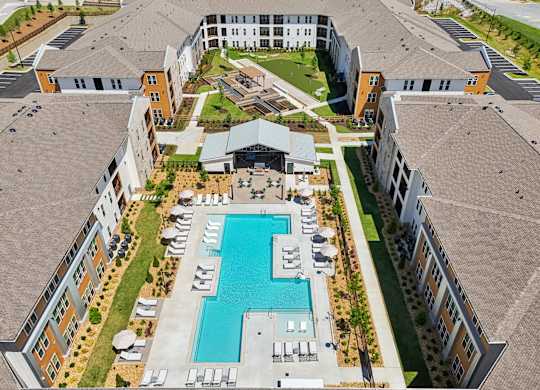 An aerial view of a large building complex with a swimming pool in the center.