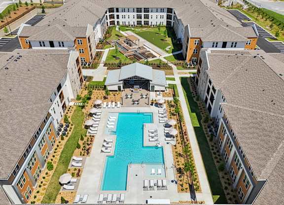 An aerial view of a large building complex with a swimming pool in the center.