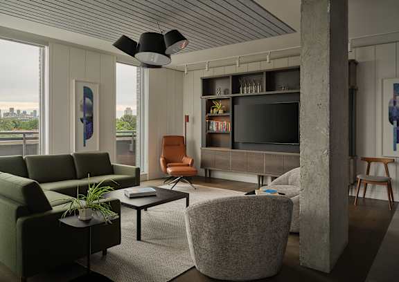 A living room with a green couch, a grey armchair, a coffee table, and a television.
