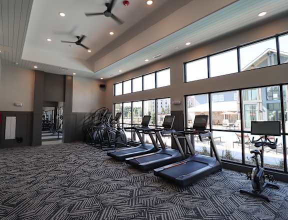 a gym with cardio equipment and windows at the district flats apartments at The Crest at Acworth, Acworth