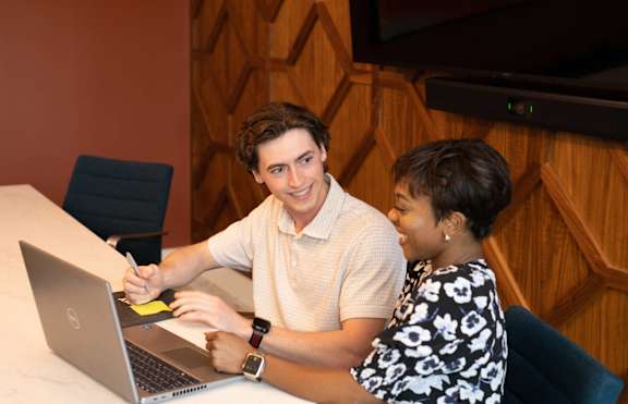 A man and a woman are sitting at a table with a laptop.