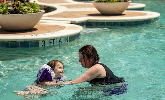 A woman and a child are swimming in a pool.