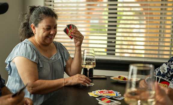 A woman is laughing while playing a card game.