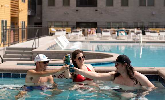 Three people are in a pool with a building in the background.
