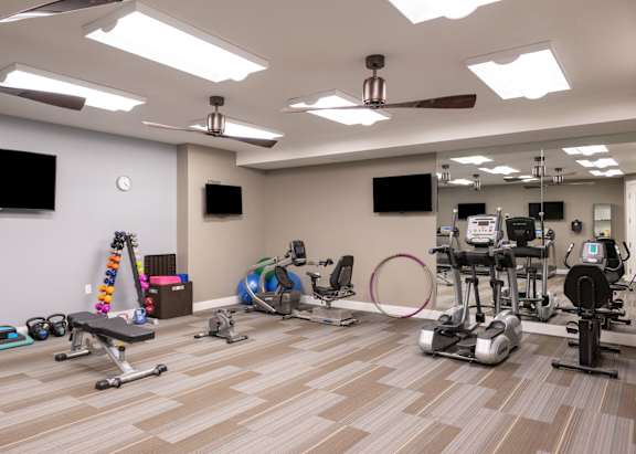 a gym with weights and cardio equipment on a wooden floor