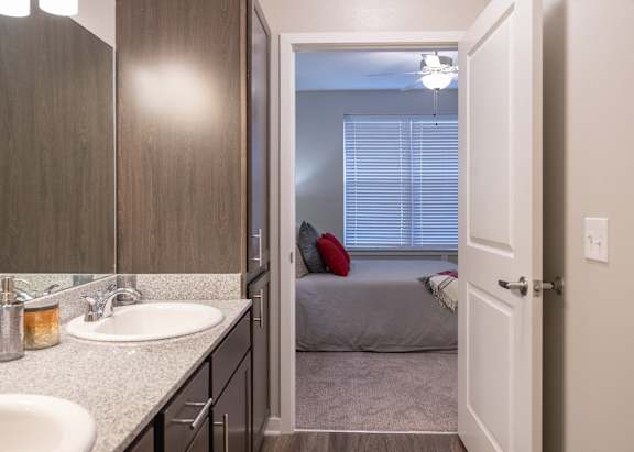 a bathroom with a sink and a mirror and a bedroom with a bed