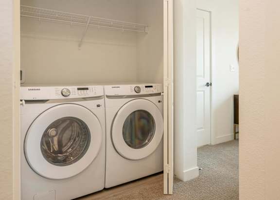 Two white Samsung front load washing machines in a laundry room.